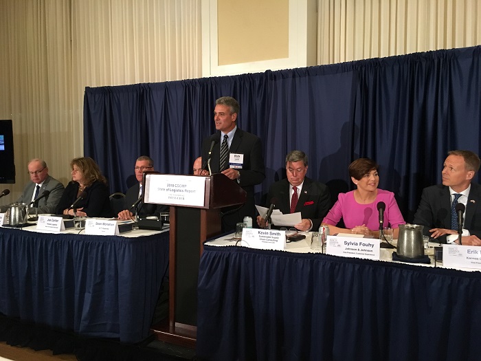 The panel discussing the "State of Logistics Report" sponsored by Penske Logistics. Left to right: Joseph Ruddy, chief innovation officer, Port of Virginia; Cheryl Capps, vice presindent of global supply chain, Corning International; Joe Carlier, Senior Vice President of global sales with Penske Logistics; Sean Monaghan, partner with A.T. Kearney; standing up speaking is Rick Blasgen, CEO of CSCMP; Kevin Smith, CEO of Sustainable Supply Chain Consulting; Sylvia Fouhy, Vice President of customer experience, Johnson and Johnson; and finally Erik Hansen, Vice President of intermodal with Kansas City Southern. Photo credit: Ari Ashe.