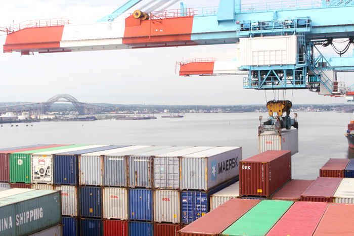 An APM Terminals crane loads containers onto a vessel in June, with the newly elevated Bayonne Bridge in the background. Photo credit: Hugh R. Morley.