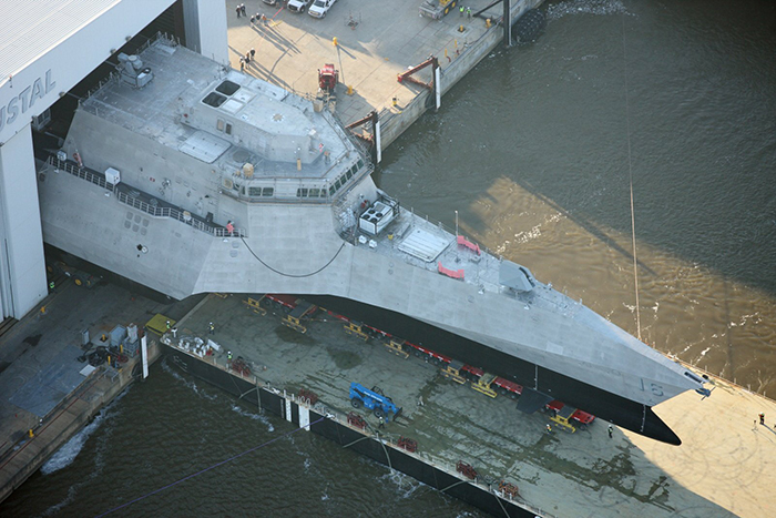A Crowley barge is positioned under littoral combat ship Tulsa as it leaves drydock.