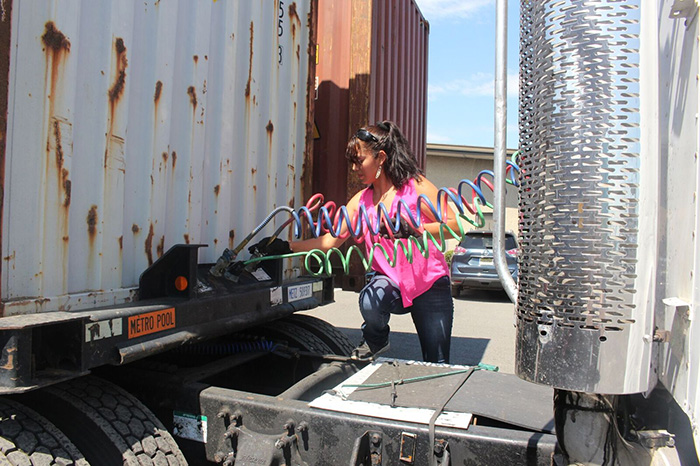 Martha Andrade, an owner-operator in the Port of New York and New Jersey for BBT Logistics. Inc., in Newark, inserts power cables as she hooks her truck up to a trailer.